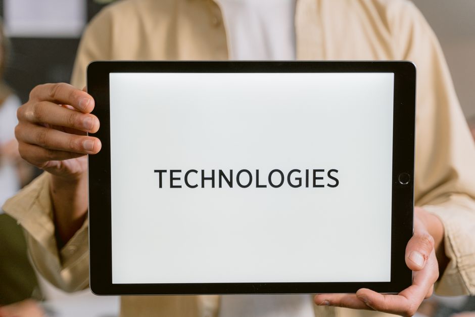 Close-up of a person holding a tablet with the word 'Technologies' on the screen.