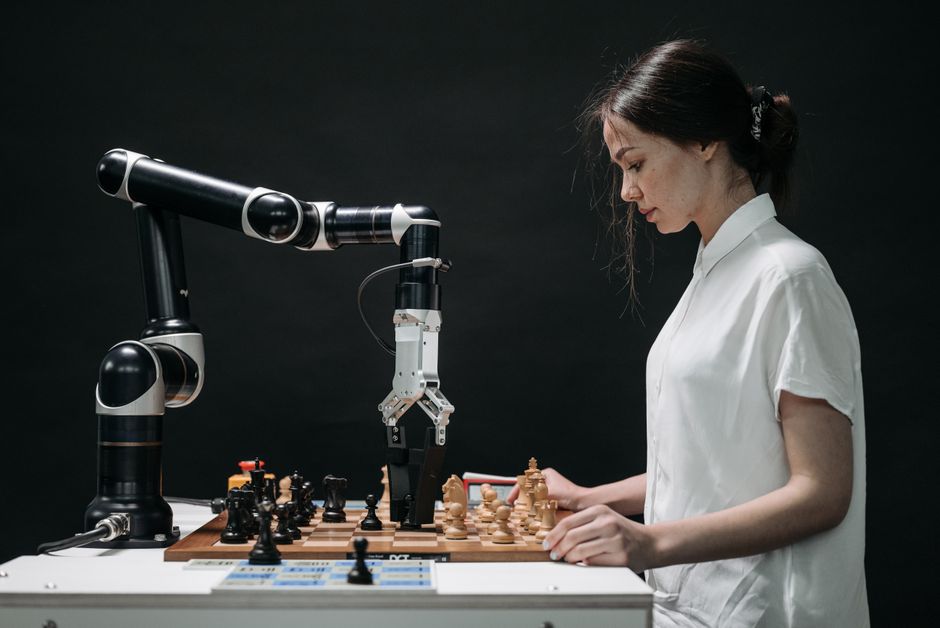 A robot and woman engage in chess, showcasing technology and strategic thinking.